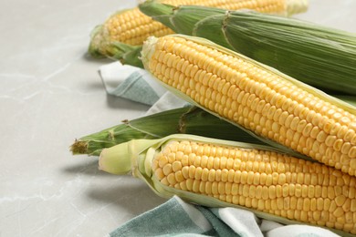 Bunch of corn cobs on light marble table, closeup