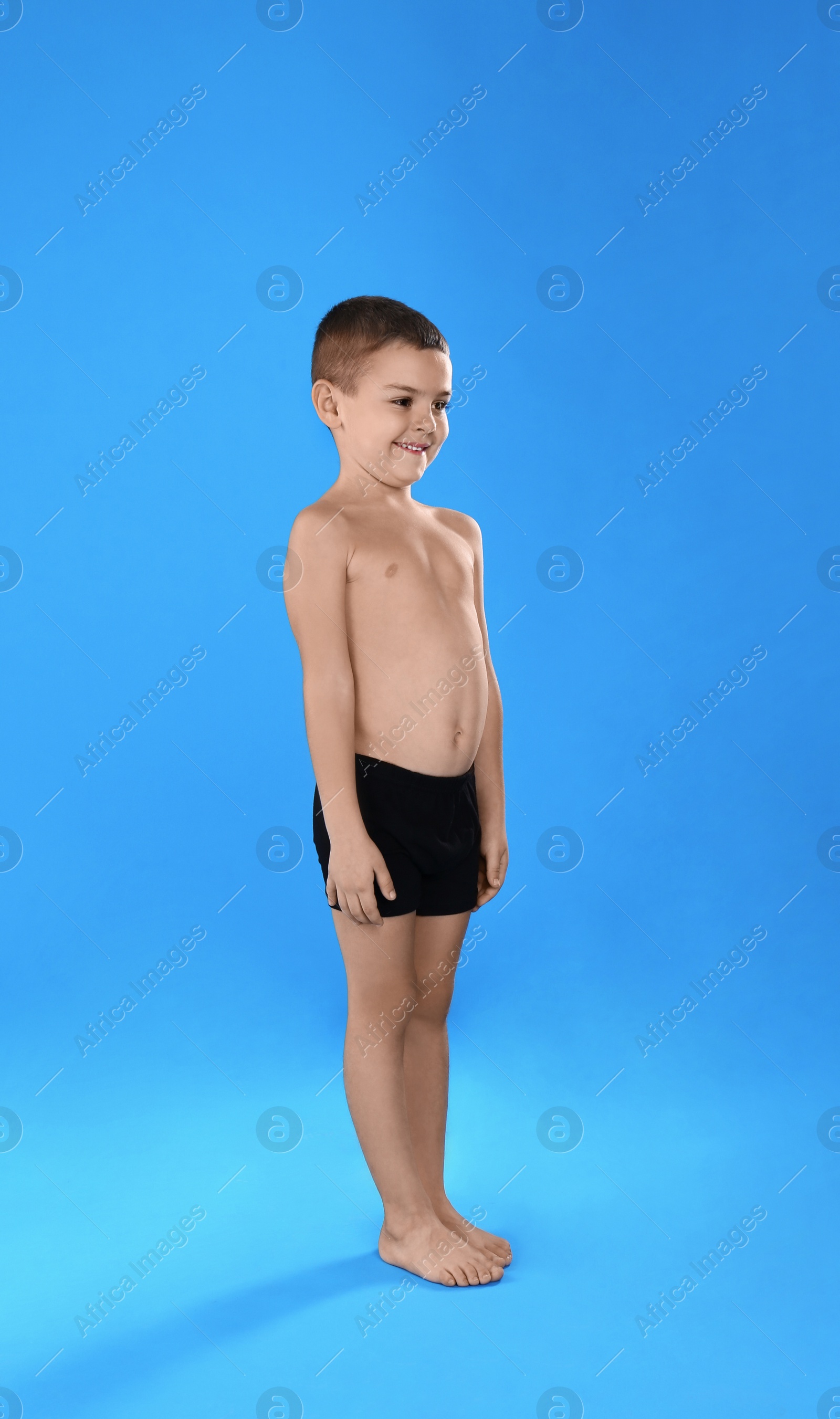 Photo of Cute little boy in underwear on light blue background