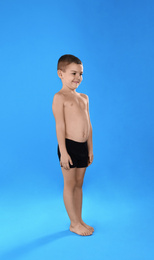 Photo of Cute little boy in underwear on light blue background