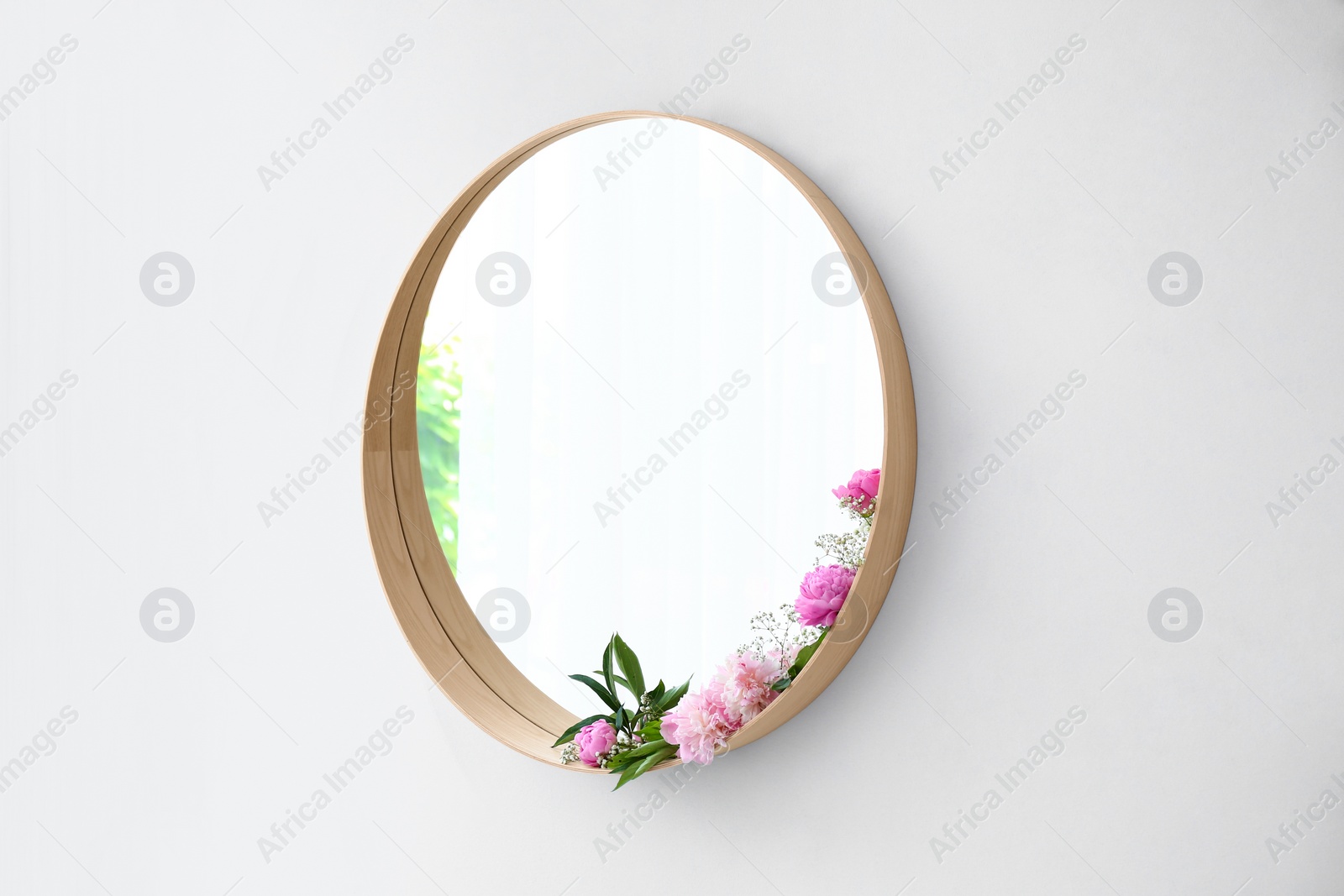 Photo of Round mirror with fresh flowers on white wall in modern room interior