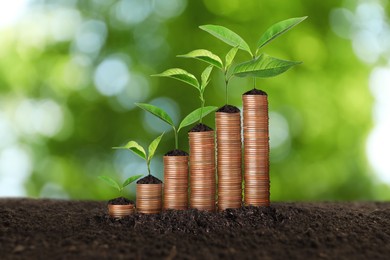 Image of Stacked coins and green seedlings on ground outdoors, bokeh effect. Investment concept