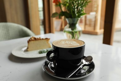 Cup of fresh coffee and dessert on table indoors