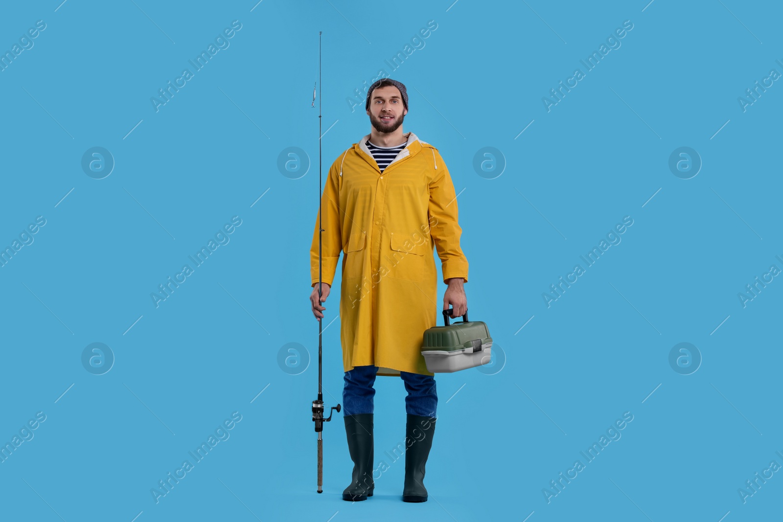 Photo of Fisherman with rod and tackle box on light blue background