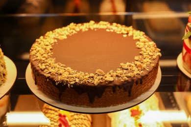 Photo of Delicious wafer cake with condensed milk, chocolate and nuts on counter in bakery shop, closeup