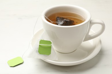 Tea bag in cup on white table, closeup