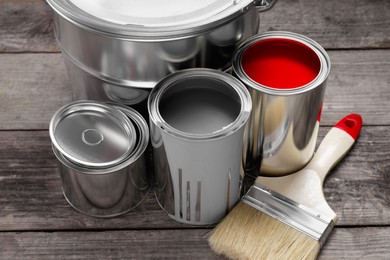 Photo of Cans of paints and brush on wooden table