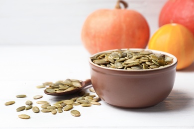 Photo of Shelled raw pumpkin seeds in dish on white table