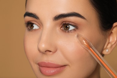 Woman using high frequency darsonval device on beige background, closeup