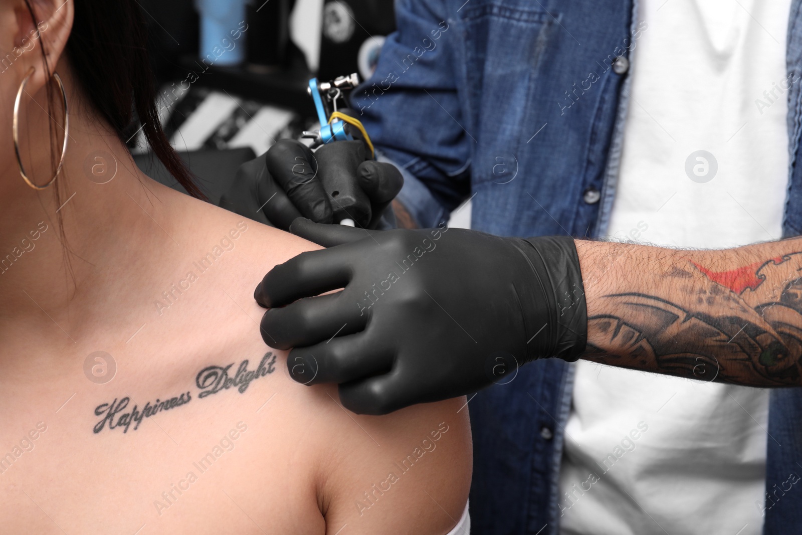 Photo of Professional artist making tattoo in salon, closeup