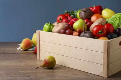 Photo of Crate full of different vegetables and fruits on wooden table, closeup. Harvesting time
