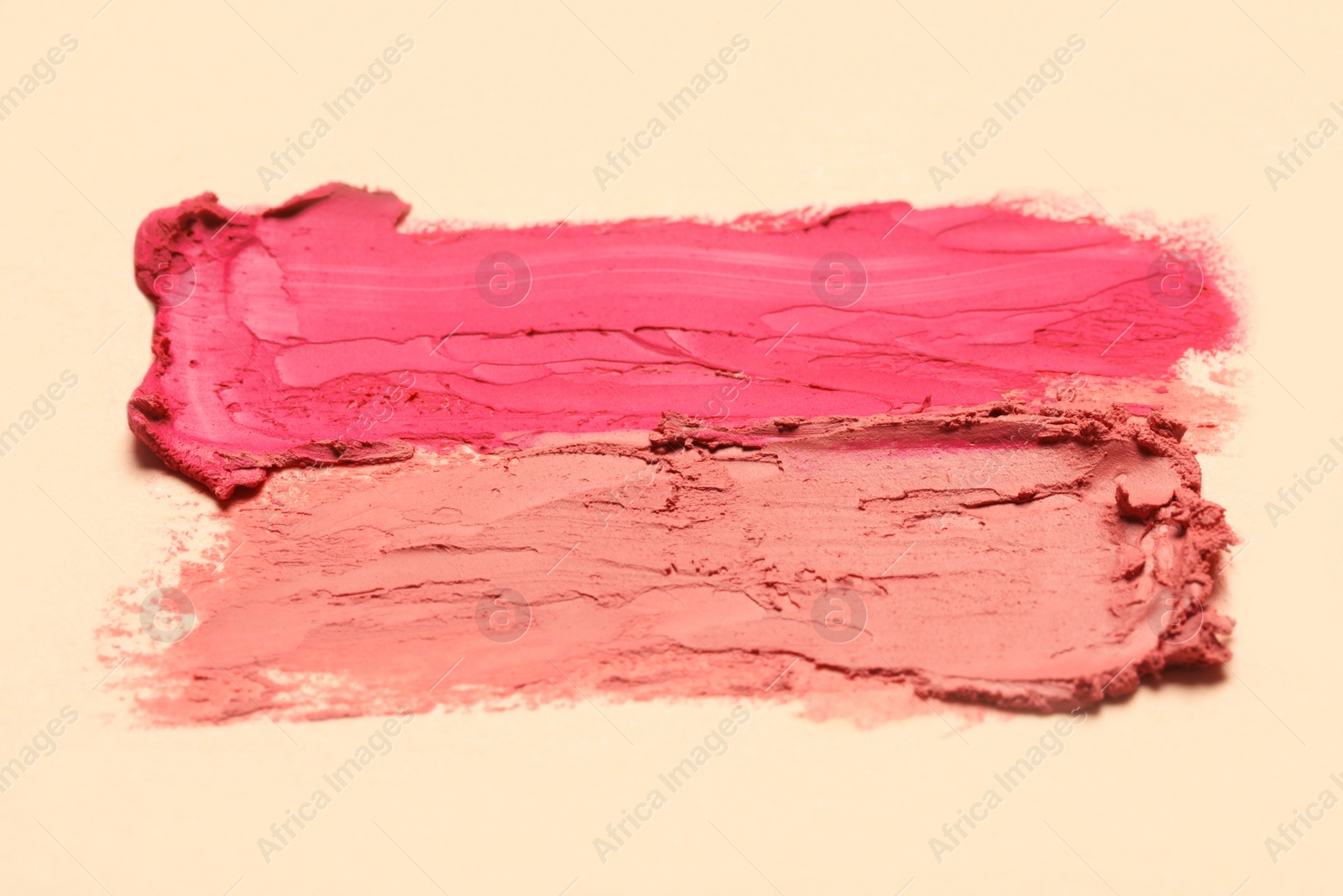 Photo of Smears of beautiful lipsticks on beige background, closeup