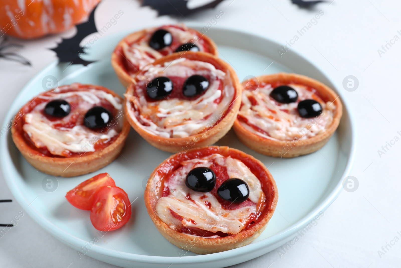Photo of Cute monster tartlets served on white table. Halloween party food