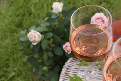 Photo of Glasses of delicious rose wine on picnic basket outdoors, closeup. Space for text
