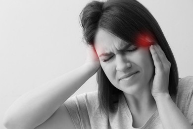 Image of Young woman suffering from migraine on light background