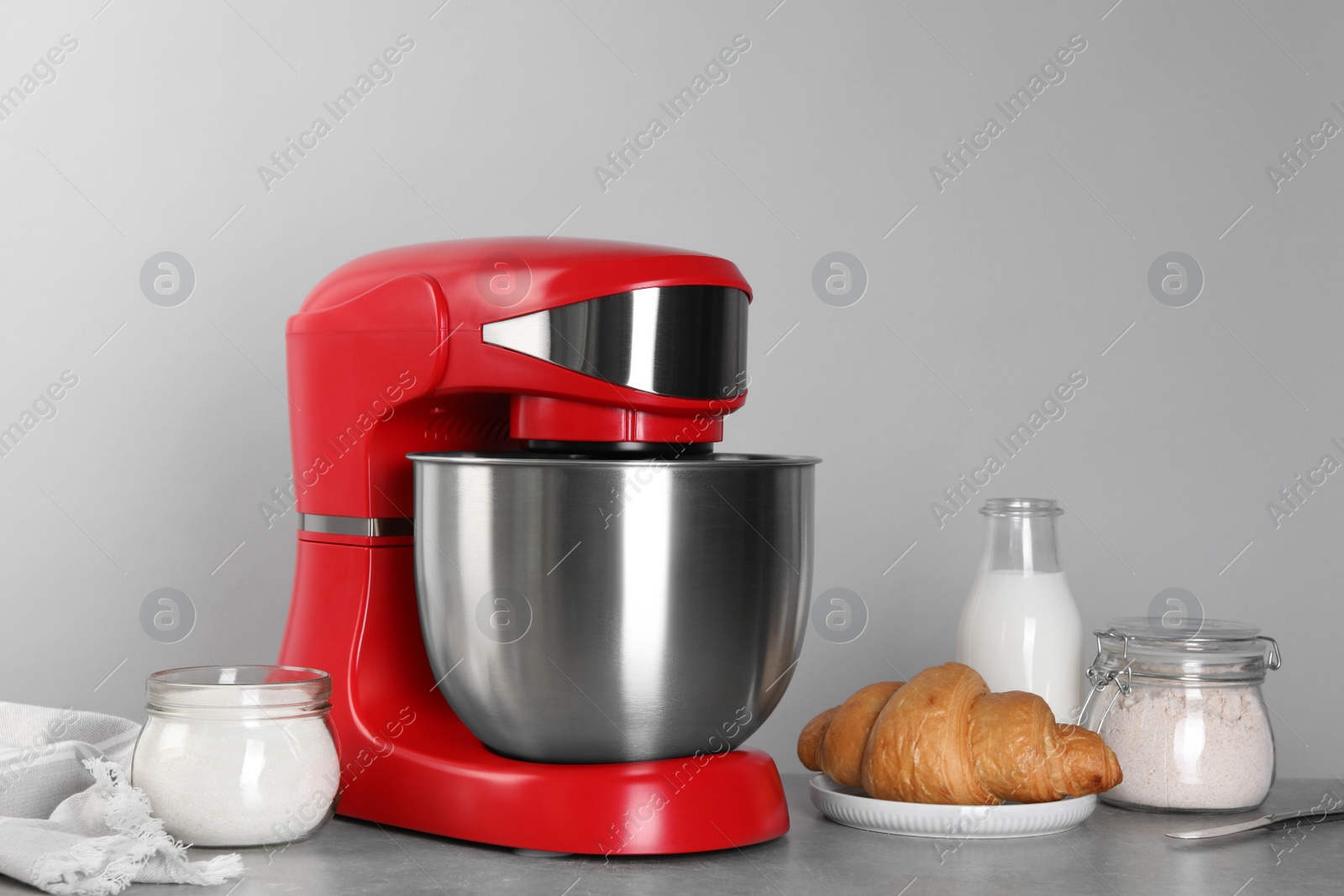 Photo of Modern red stand mixer, croissant and ingredients on gray marble table