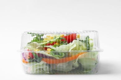 Photo of Plastic container with fresh salad on white background