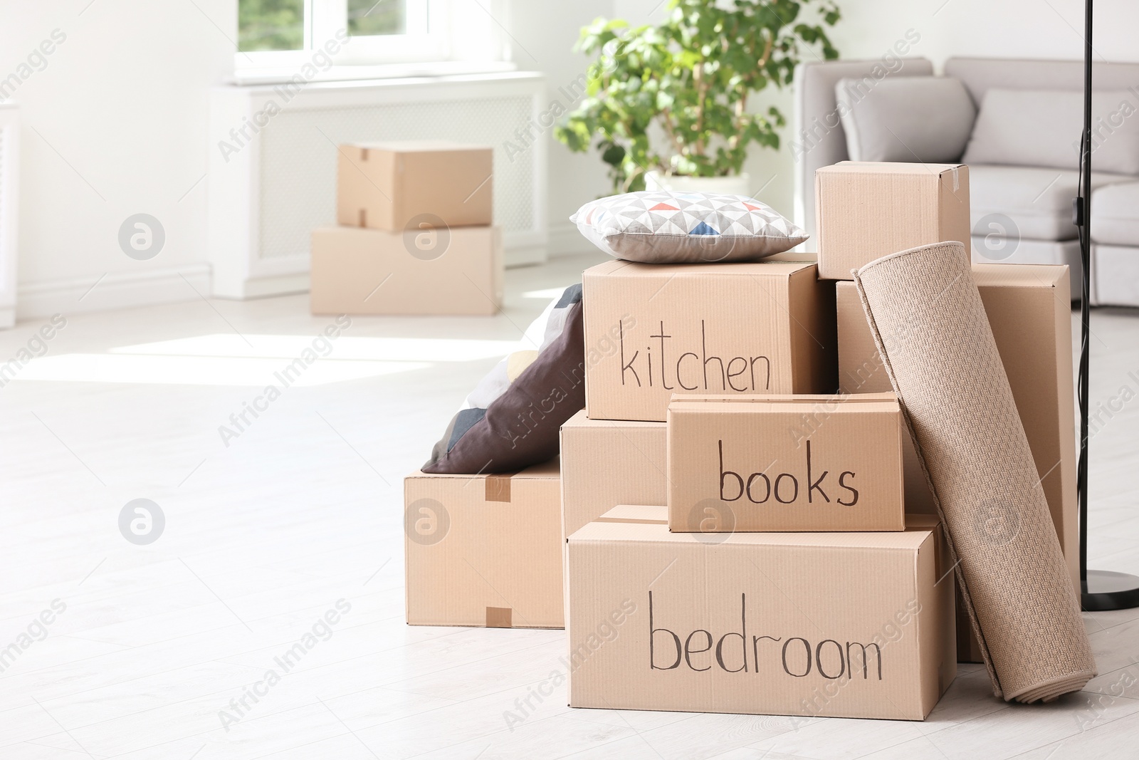 Photo of Pile of moving boxes and household stuff in living room