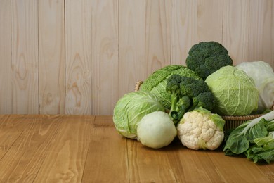 Many different types of fresh cabbage on wooden table. Space for text