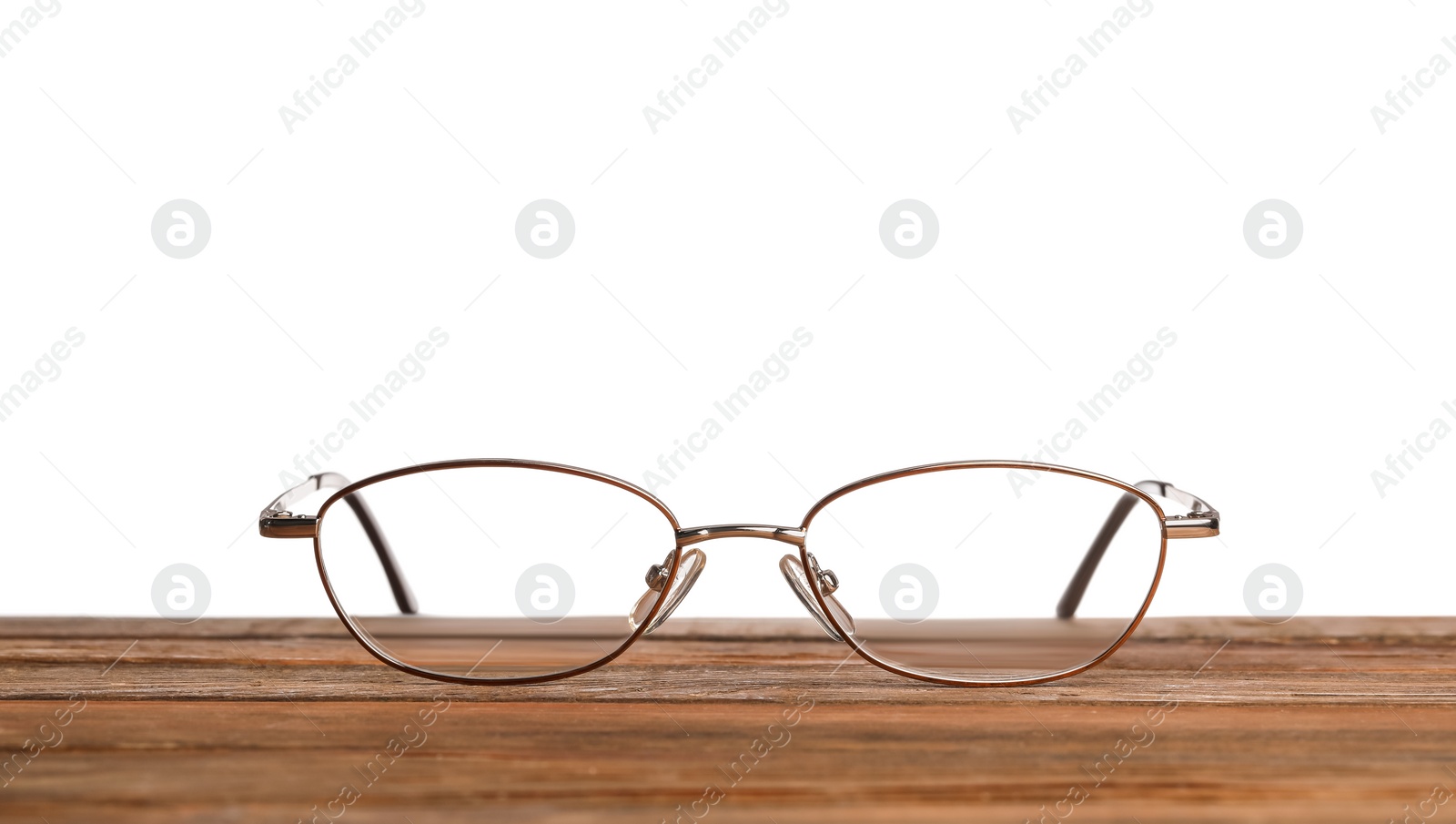 Photo of Stylish glasses with metal frame on wooden table against white background