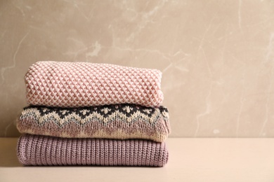 Photo of Stack of warm knitted clothes on table