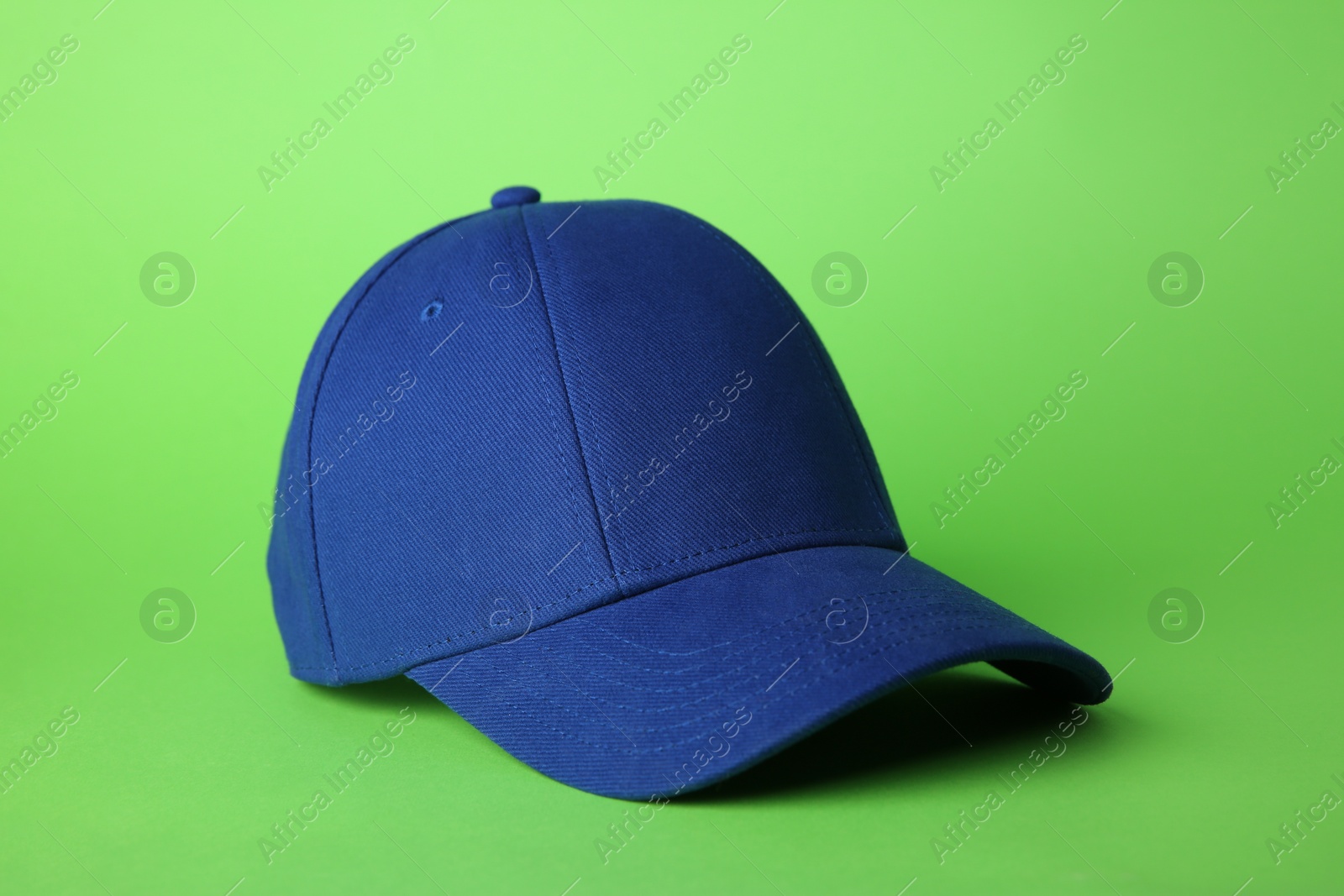 Photo of Stylish blue baseball cap on light green background