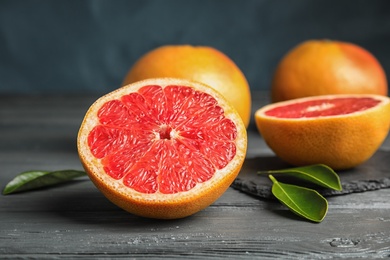 Photo of Whole and sliced tasty grapefruits on table