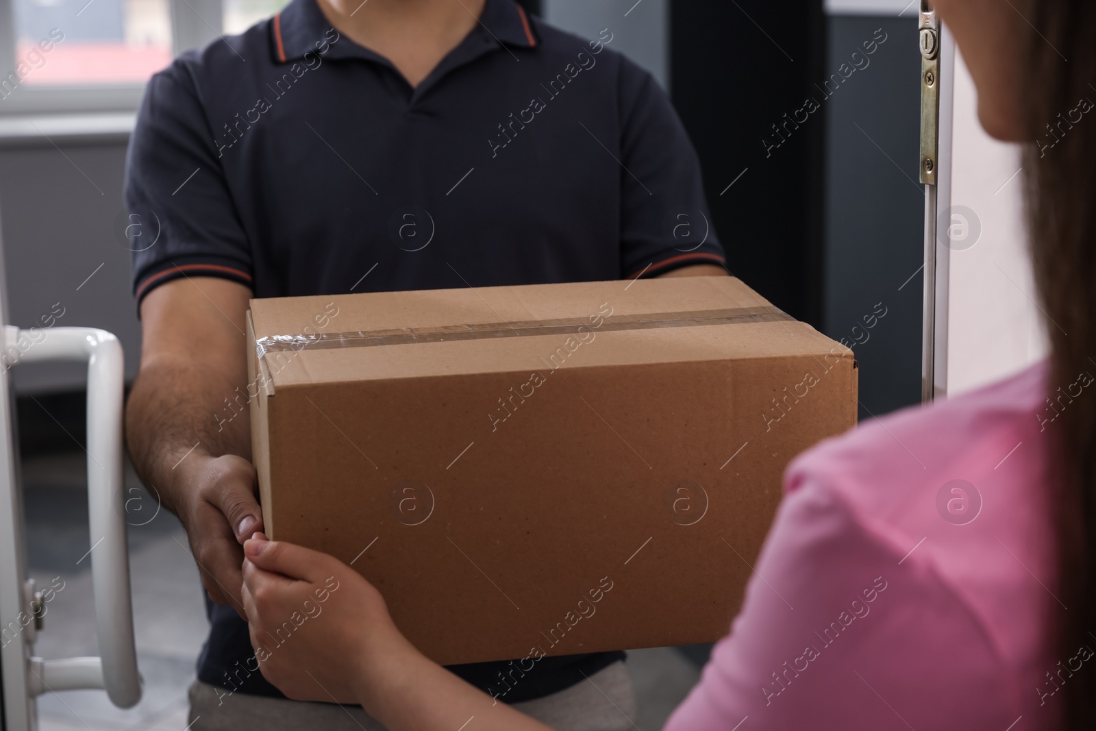 Photo of Woman receiving parcel from courier at home, closeup