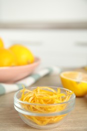 Photo of Grated lemon zest in bowl on wooden table