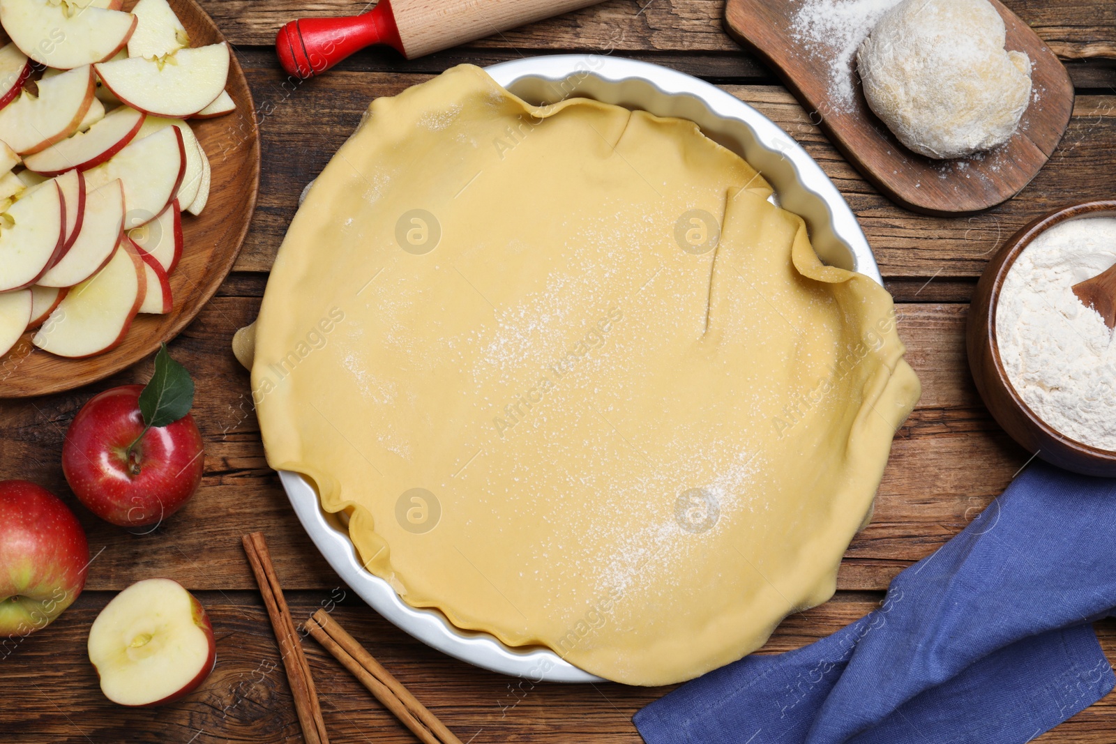 Photo of Flat lay composition with raw dough and ingredients on wooden table. Baking apple pie