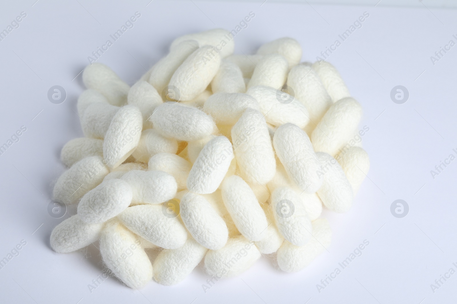 Photo of Pile of natural silkworm cocoons on white background, above view