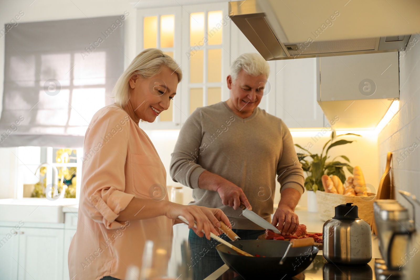 Photo of Mature couple cooking food together in kitchen