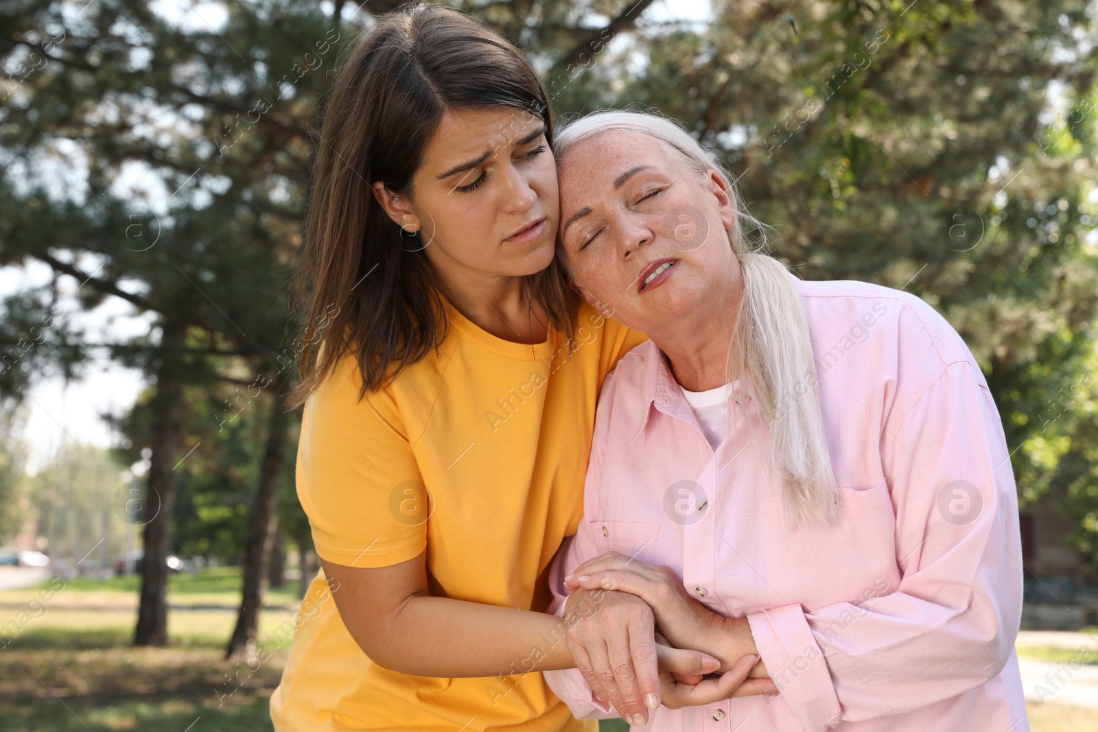 Photo of Woman helping mature lady in park. Suffering from heat stroke