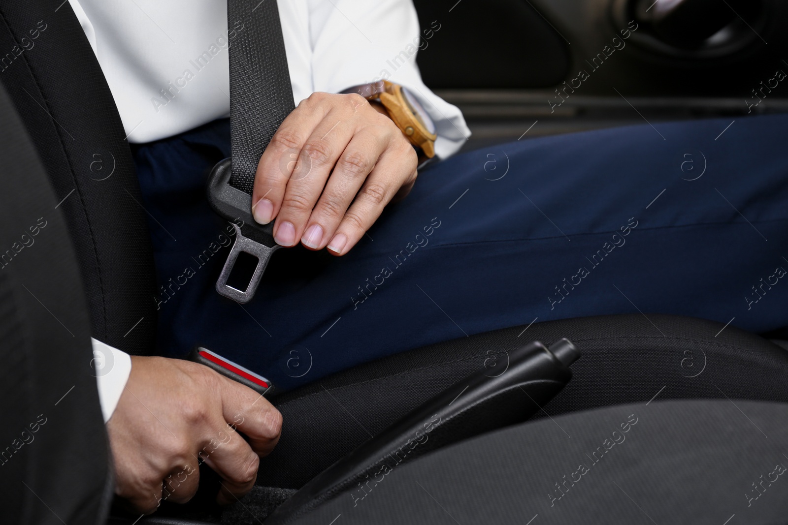 Photo of Woman fastening safety belt on driver's seat in car, closeup