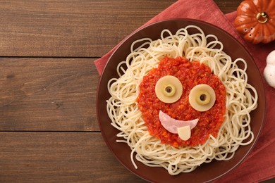 Photo of Plate with funny monster made of tasty pasta served on wooden table, flat lay with space for text. Halloween food