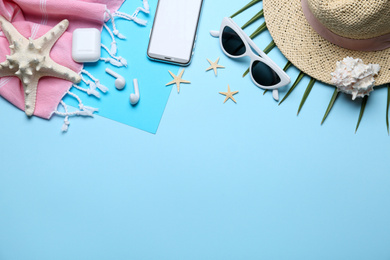 Flat lay composition with beach accessories on light blue background, space for text