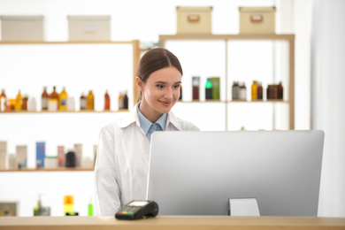 Photo of Professional pharmacist working with computer in drugstore