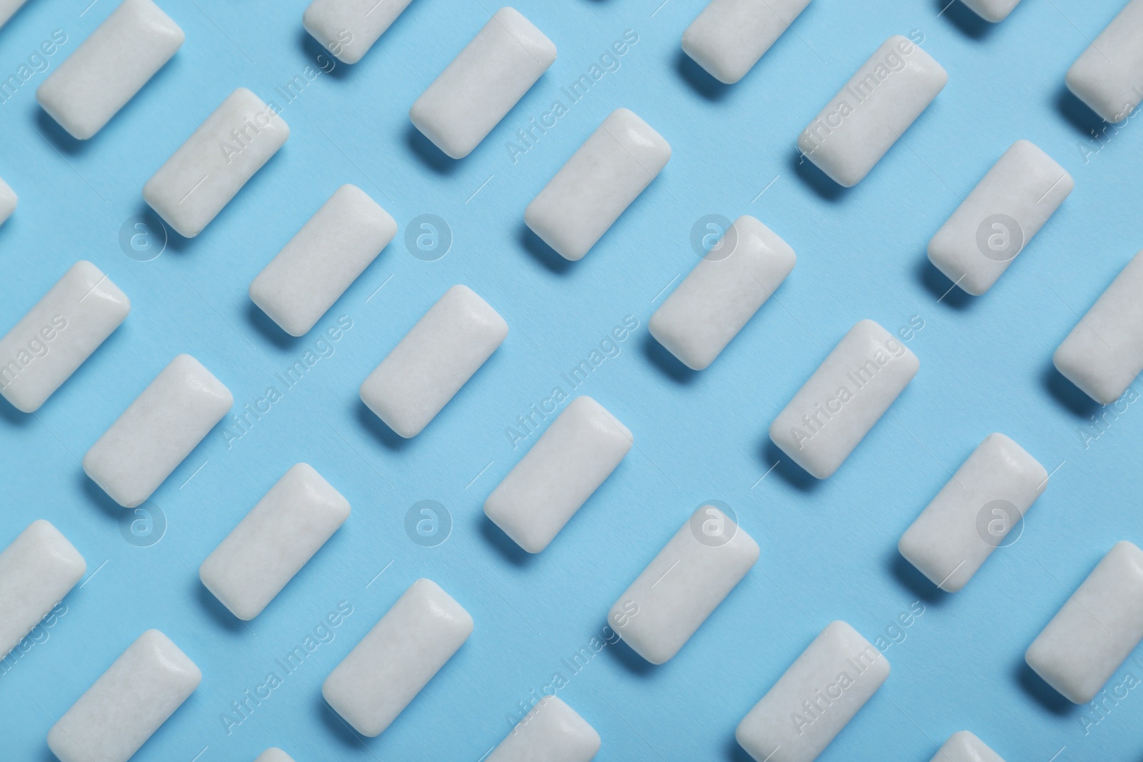 Photo of Tasty white chewing gums on light blue background, flat lay