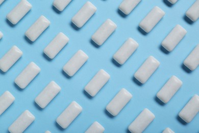 Tasty white chewing gums on light blue background, flat lay