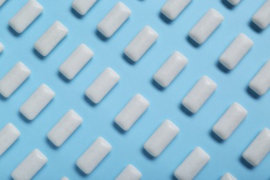 Photo of Tasty white chewing gums on light blue background, flat lay