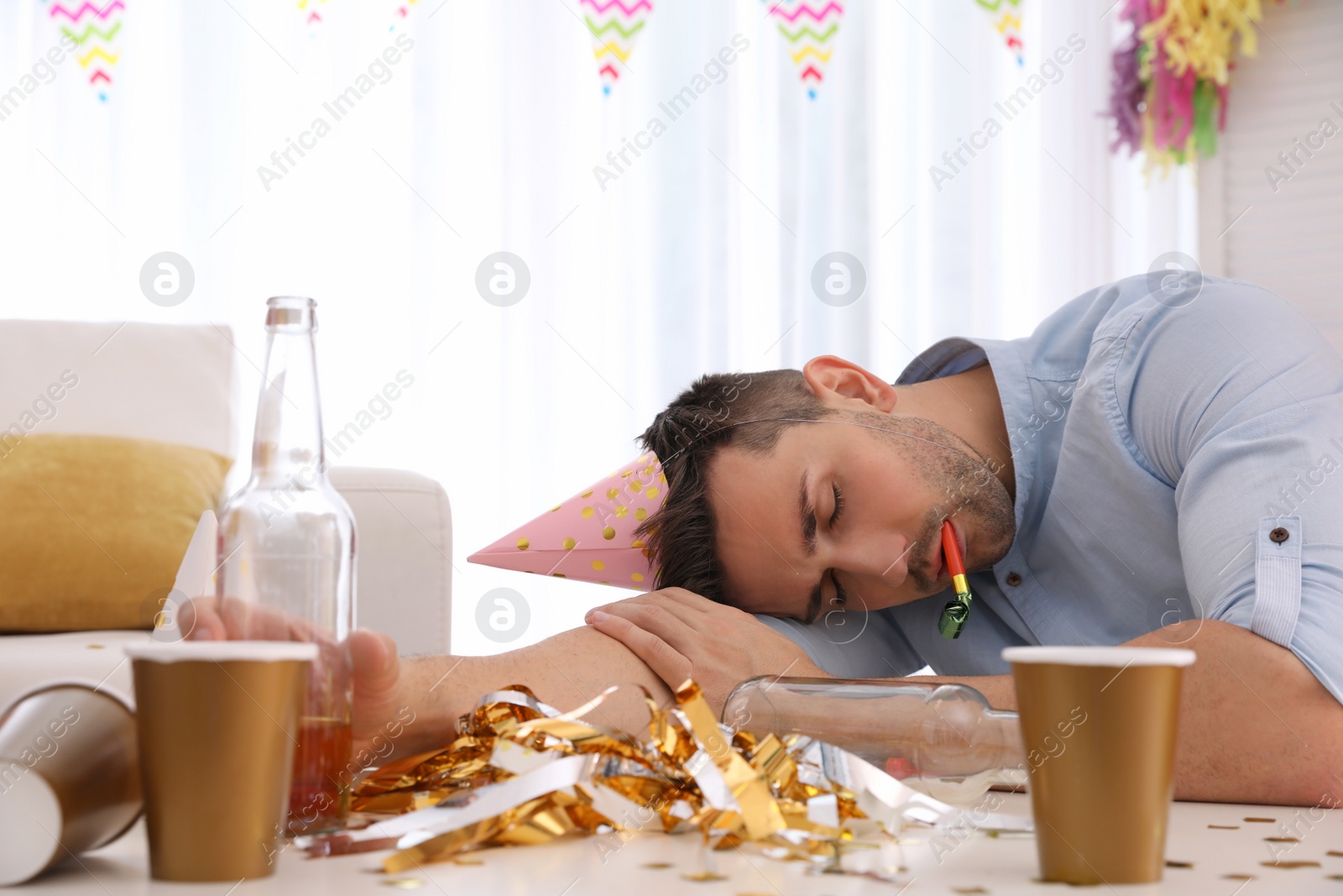 Photo of Young man with festive cap sleeping at table after party