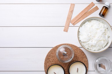 Flat lay composition with homemade candles and ingredients on white wooden background, space for text