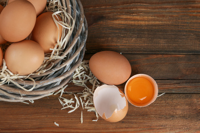 Photo of Raw chicken eggs on wooden table, flat lay