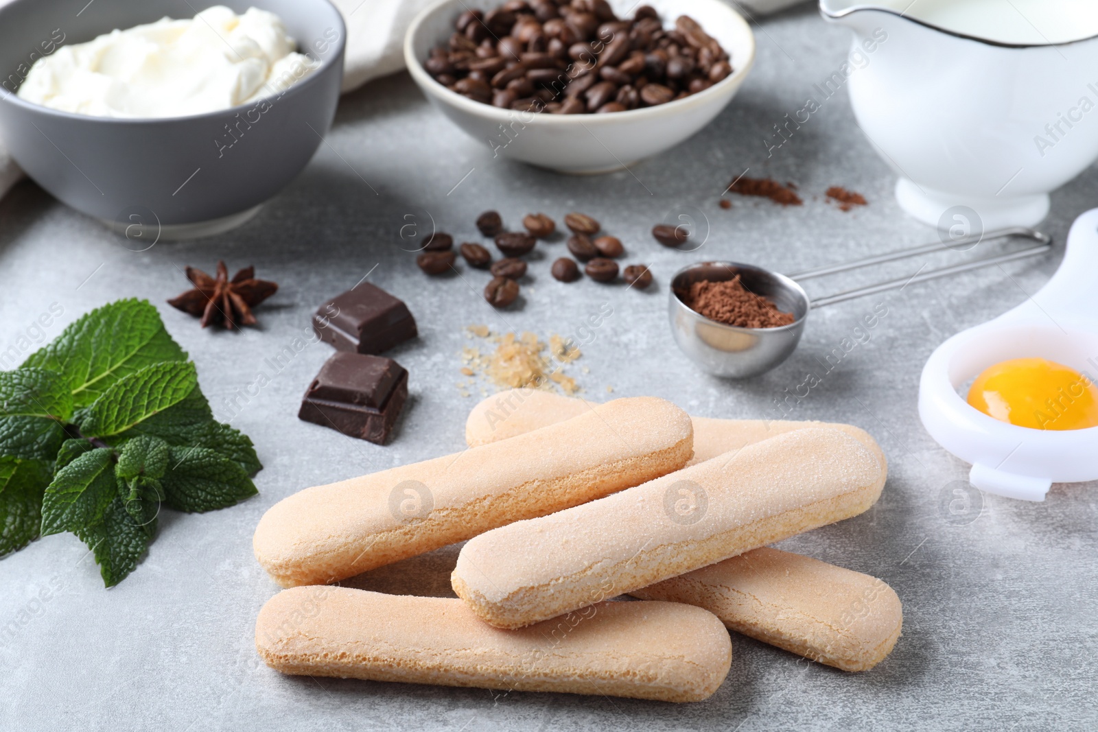 Photo of Tasty cookies and other ingredients for tiramisu on grey table