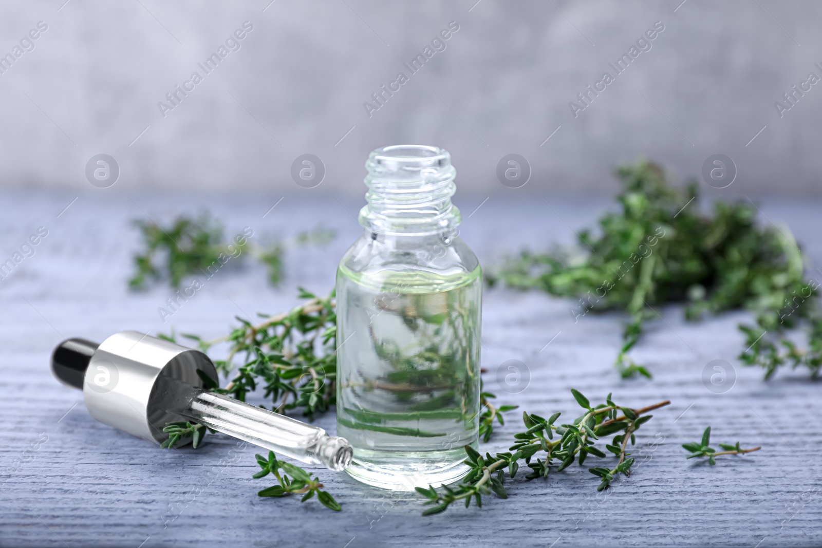 Photo of Thyme essential oil on light blue wooden table