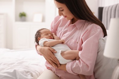 Photo of Mother with her sleeping newborn baby on bed at home