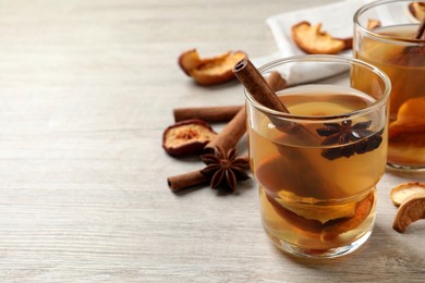 Photo of Delicious compote with dried apple slices, anise and cinnamon on white wooden table. Space for text