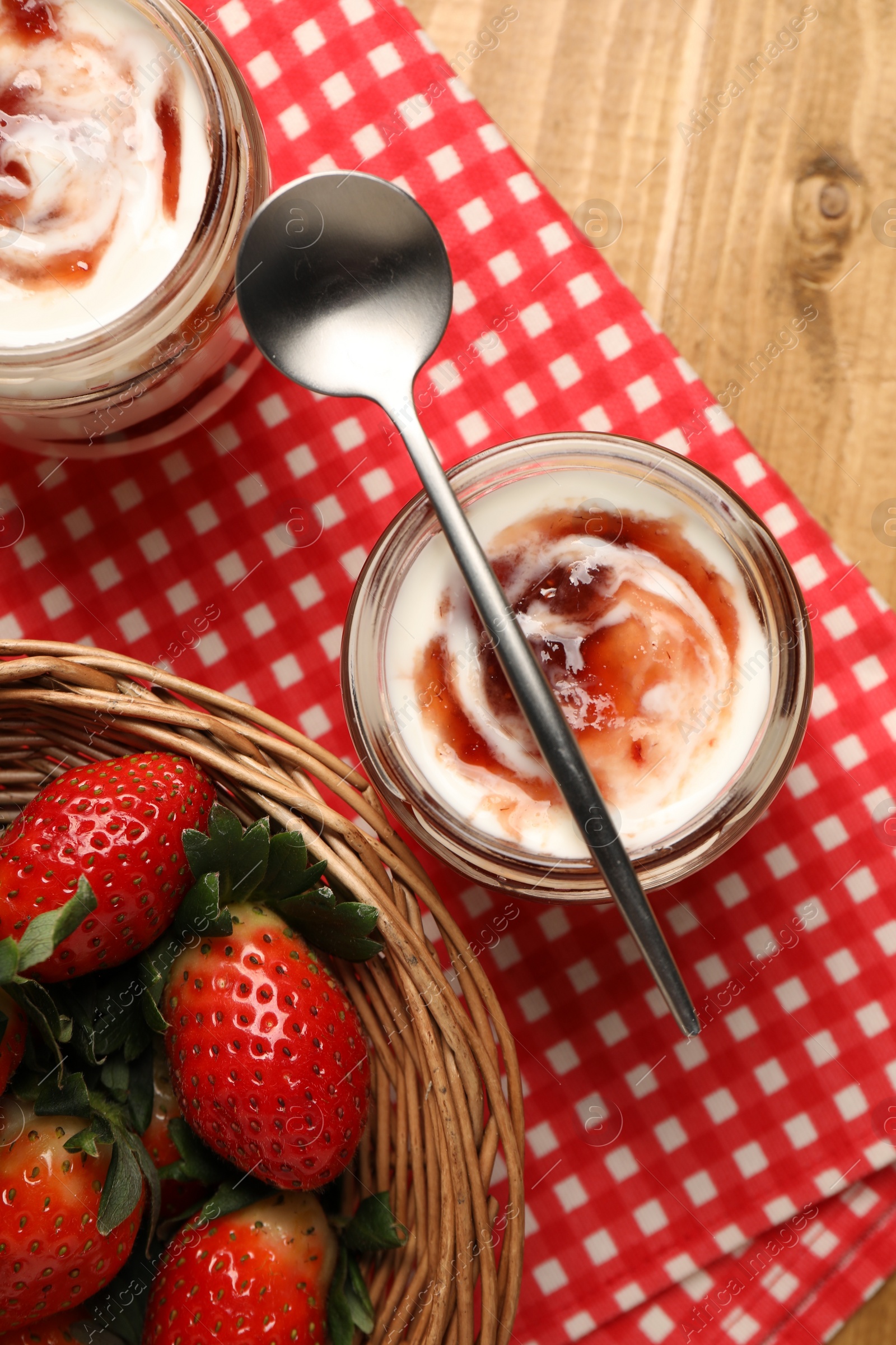 Photo of Tasty yoghurt with jam and strawberries on wooden table, top view