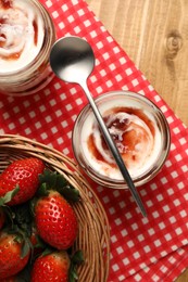 Photo of Tasty yoghurt with jam and strawberries on wooden table, top view