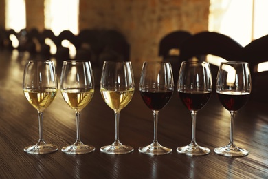 Photo of Glasses of white and red wines on wooden table