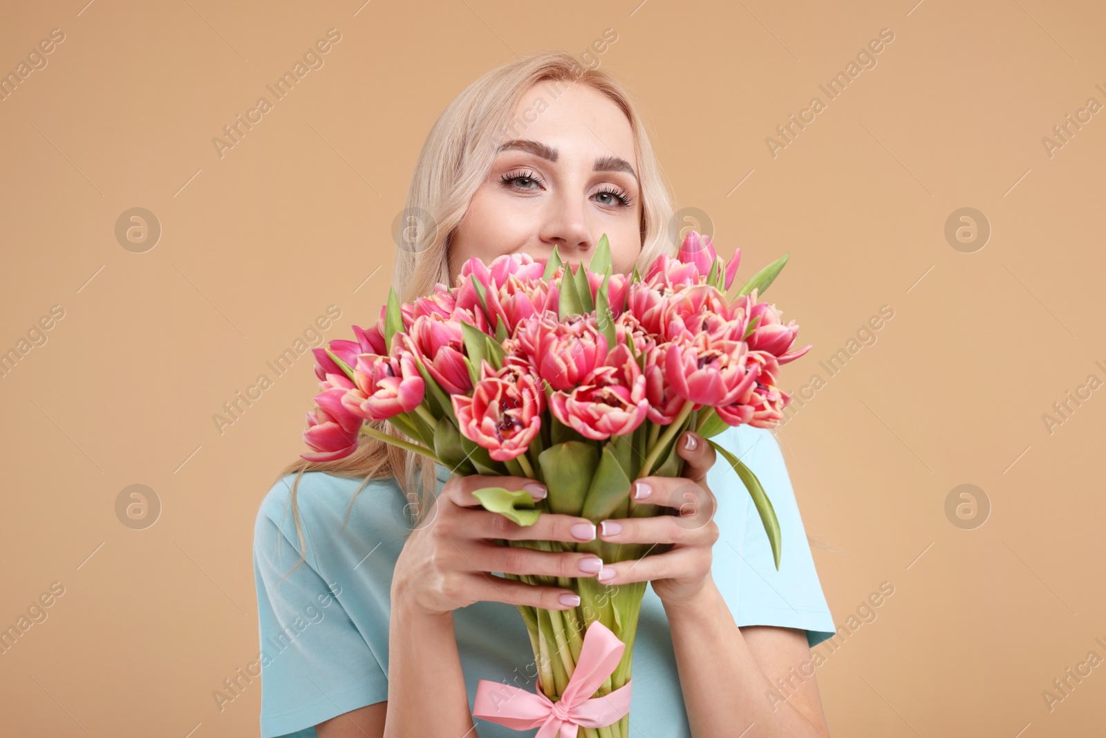 Photo of Happy young woman with beautiful bouquet on beige background